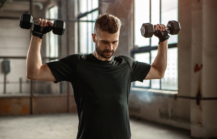 strong man exercising with dumbbells in gym